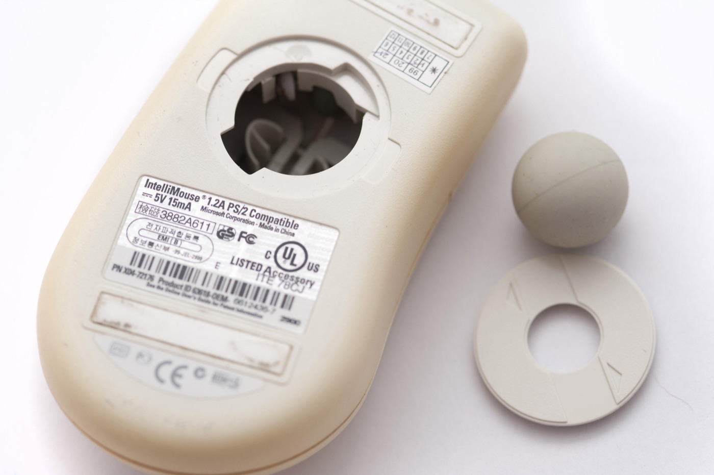 The underside of a yellowed Microsoft IntelliMouse with its rubber ball and retaining ring taken out.